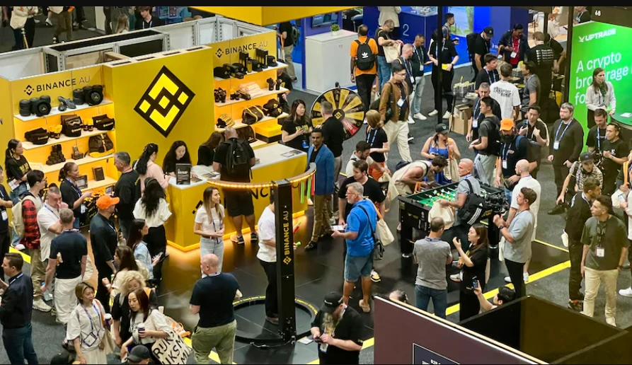 Visitors talking and exploring exhibitor booths at a crypto industry event